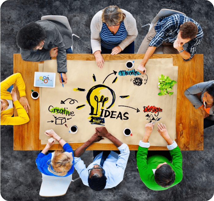 A group of people sitting around a table with an idea written on it.