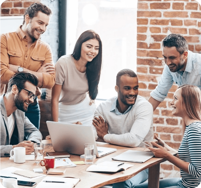 A group of people sitting around a table with a laptop.